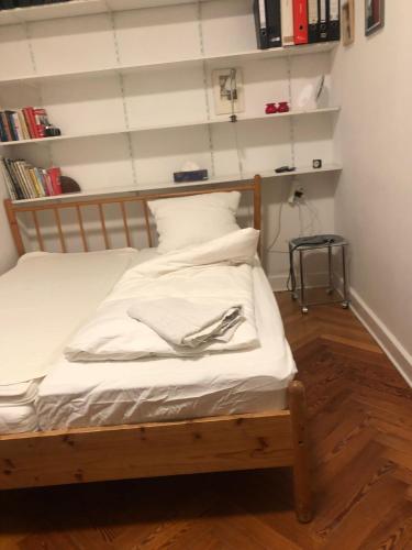 Schlafzimmer mit einem Bett mit weißer Bettwäsche und Bücherregalen in der Unterkunft Dream cuddle Nest in Berlin