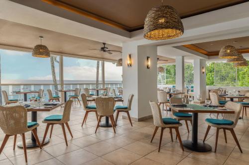 a dining room with tables and chairs and windows at Waves Resort & Spa, Barbados, An Autograph Collection All-Inclusive Resort in Saint James