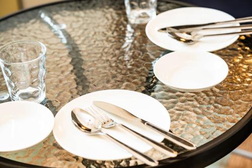 a glass table with white plates and silverware on it at 高原マンション 205 in Matsuyama