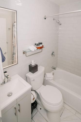 a white bathroom with a toilet and a bath tub at Pantai Inn in San Diego