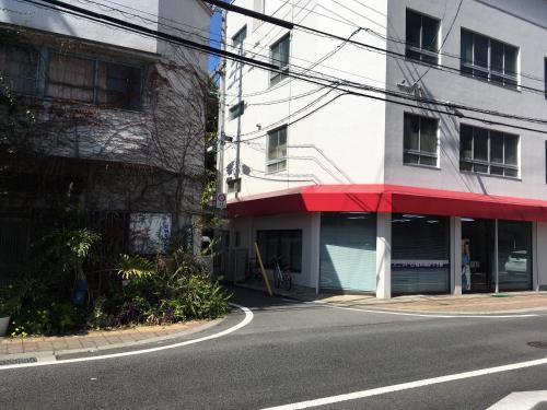 a building with a red awning next to a street at 高原マンション 202 in Matsuyama