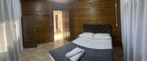 ein Schlafzimmer mit einem Bett und einer Holzwand in der Unterkunft Casa Jardinada in Pomerode