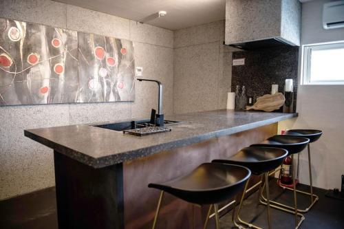 a kitchen with a counter with bar stools and a sink at Sauna Villa Yoichi / 4 bed room with private sauna in Kurokawamachi