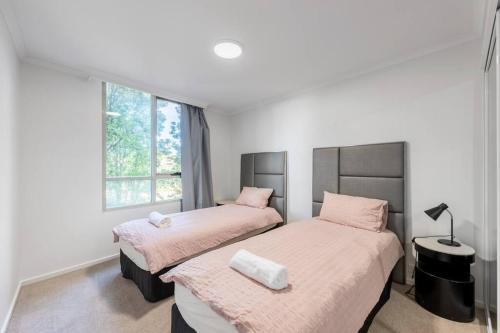 two beds in a room with two windows at Serain Apartment on Northbourne Ave Canberra in Canberra