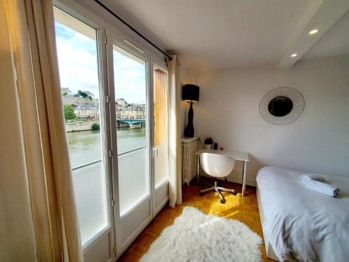 蓬圖瓦茲的住宿－Le Loft de L’Écluse / F2 cosy au bord de l'eau，一间卧室设有大窗户、一张床和一张书桌