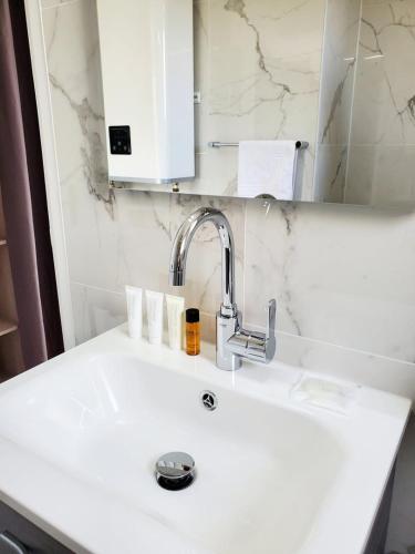 un lavabo blanc dans une salle de bain avec un miroir dans l'établissement Le Loft de L’Écluse / F2 cosy au bord de l'eau, à Pontoise