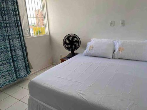 um quarto com uma cama branca e uma janela em Apt inteiro bem localizado com Wi-Fi e aceita Pets em Aracaju