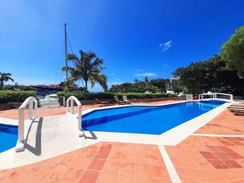 a blue swimming pool with a palm tree in the background at Penthouse, Ocean & Marina vws, Great 4 Remote Work in Puerto Aventuras