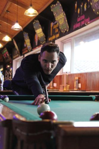 a man leaning over a pool table with a cue at Pariwana Hostel Cusco in Cusco