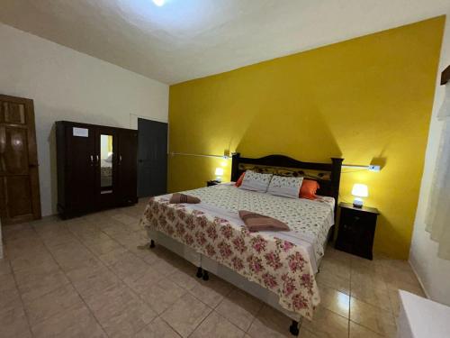 sypialnia z łóżkiem i żółtą ścianą w obiekcie Casa Maya Itza w mieście Flores