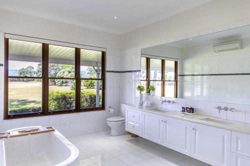 a bathroom with a tub and a sink and a toilet at The Hampton Lodge with private pool on 25 acres in Port Douglas