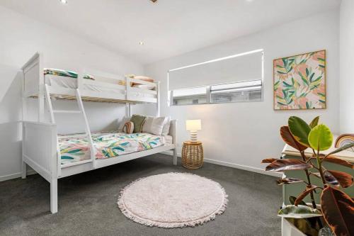 een witte slaapkamer met een stapelbed en een tapijt bij Zinc Casuarina in Casuarina
