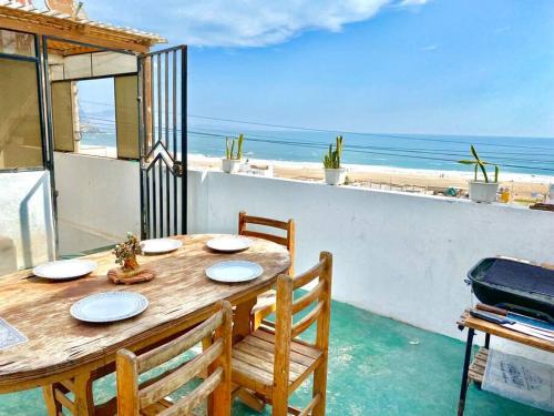 un tavolo in legno con sedie e una vista sulla spiaggia di Habitación y terraza con vista al mar a Lima