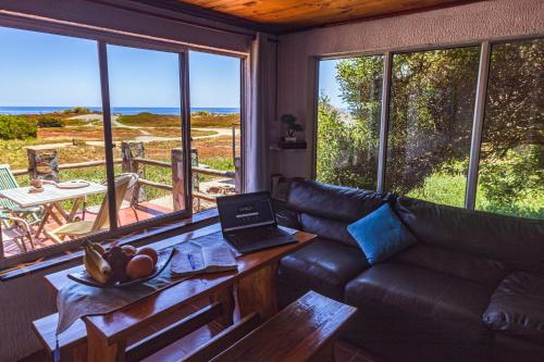 sala de estar con sofá y mesa con ordenador portátil en Hermosa Casa OlaSurf Punta de Lobos & Marbox 7 en Pichilemu