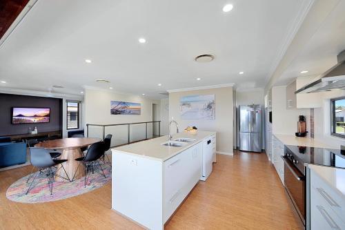 a kitchen with white cabinets and a table and a counter at Nudibranch House in Bargara