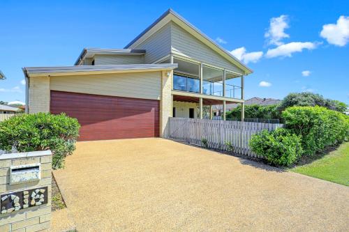 a house with a red garage door in front of it at Nudibranch House in Bargara