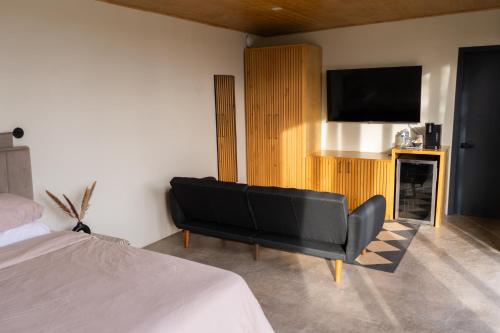 a bedroom with a black couch and a flat screen tv at MiLu in El Porvenir
