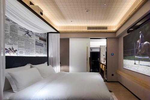 a bedroom with a large white bed with a poster on the wall at Paco Hotel Canton Tower Pazhou-Free shuttle bus for canton fair in Guangzhou
