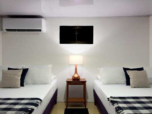 two beds in a room with a lamp on a table at Casa Caoba AC near Guanacaste Airport in Liberia