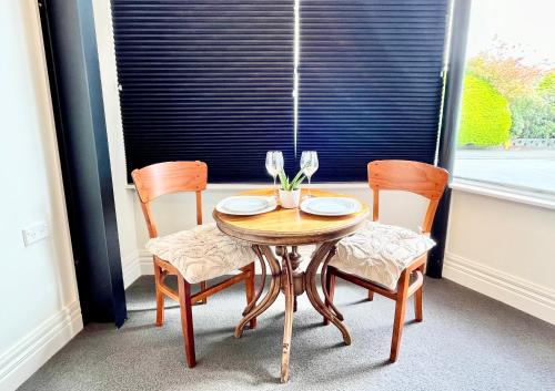 une table en bois avec deux chaises et une fenêtre dans l'établissement Opoho Heritage Guest Suite, à Dunedin