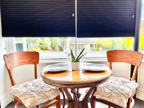 une table à manger avec deux chaises et une fenêtre dans l'établissement Opoho Heritage Guest Suite, à Dunedin