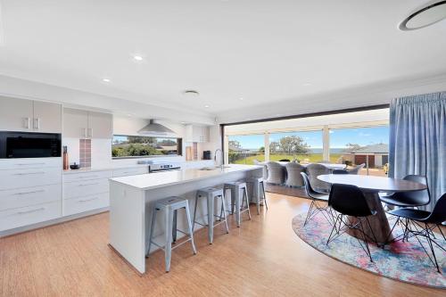 a kitchen with white cabinets and a table and chairs at Nudibranch House in Bargara