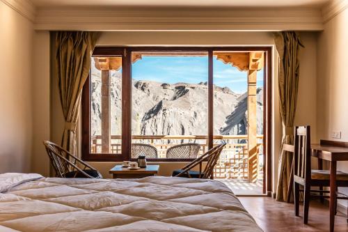 a bedroom with a view of a mountain through a window at The Legacy Alchi in Leh