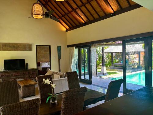 Villa Buddha Umalas في كيروبوكان: غرفة معيشة مع طاولة وكراسي ومسبح