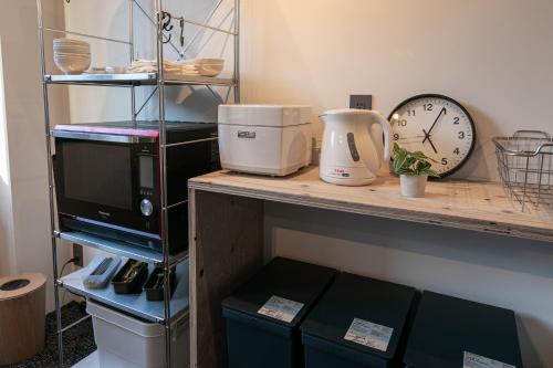 a counter with a microwave and a clock on it at City Center Villas ゲストハウス35 supported by COCOSTAY in Hijiyamachō