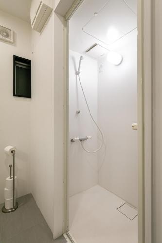 a white bathroom with a shower and a television at City Center Villas ゲストハウス35 supported by COCOSTAY in Hijiyamachō