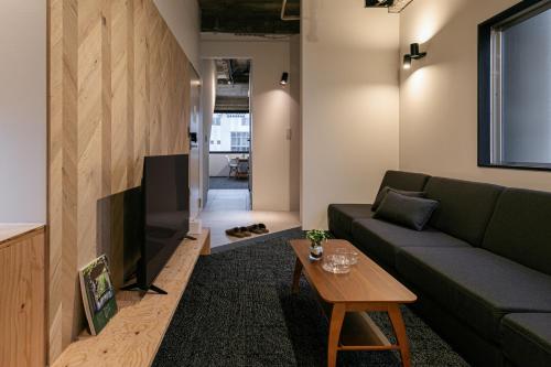 a living room with a green couch and a table at City Center Villas ゲストハウス35 supported by COCOSTAY in Hijiyamachō