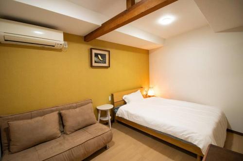 a bedroom with a bed and a couch at BRUCE GUESTHOUSE KIX in Izumi-Sano