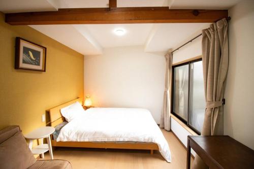een slaapkamer met een wit bed en een raam bij BRUCE GUESTHOUSE KIX in Osaka