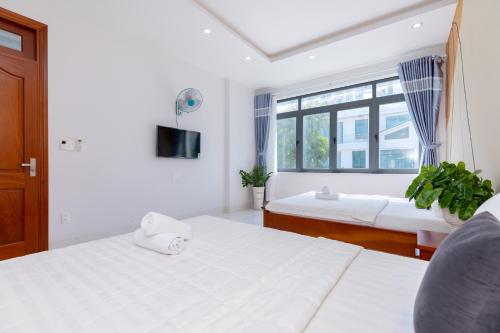 a white bedroom with two beds and a window at B2.11 Hoàng My Villa in Vung Tau