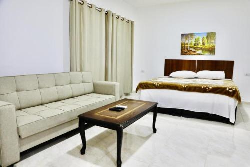 a bedroom with a bed and a couch and a table at Salvador Dali Apartments in Amman