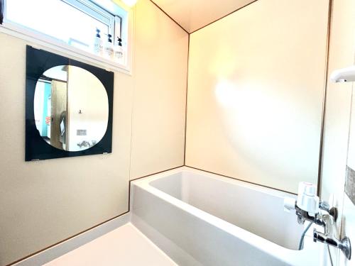 a bathroom with a bath tub and a mirror at Lavie plus in Noboribetsu
