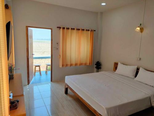 a bedroom with a bed and a view of the beach at กุหลาบแก้ว รีสอร์ท in Ban Mae Lai