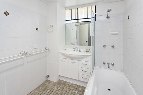 a white bathroom with a sink and a shower at Cosy Unit with Parking near New Farm Park & River in Brisbane