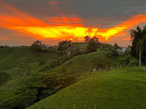 a sunset over a green hill with a house on it at Villa Jair Hotel in Filandia