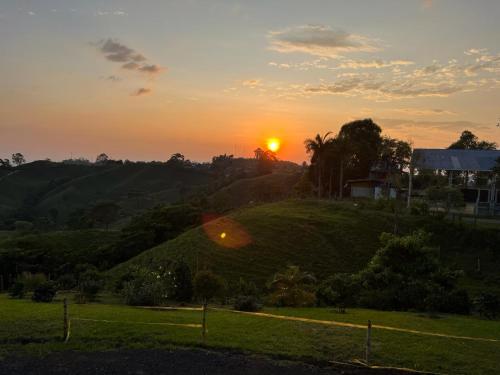 a sunset over a grassy hill with the sun setting at Villa Jair Hotel in Filandia