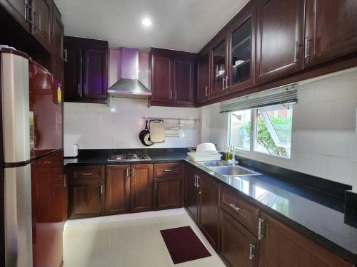 a kitchen with wooden cabinets and a sink and a window at D34长住优惠房-芭提雅市中心高端4间卧室泳池别墅 in Pattaya