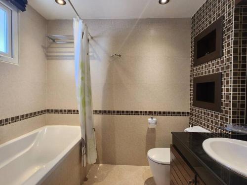 a bathroom with a tub and a toilet and a sink at D34长住优惠房-芭提雅市中心高端4间卧室泳池别墅 in Pattaya Central
