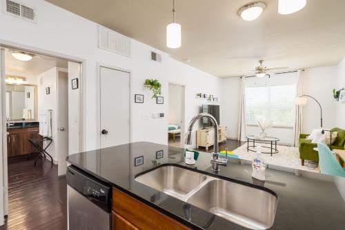 a kitchen with a sink and a living room at Alamo Chic King Bed Refreshing Office Desk w/ Pool in San Antonio