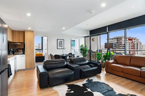 a living room with black leather furniture and a kitchen at Frank & Franki @ West Franklin in Adelaide