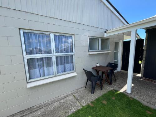 a table and chairs on the side of a house at House of Somer in Matamata