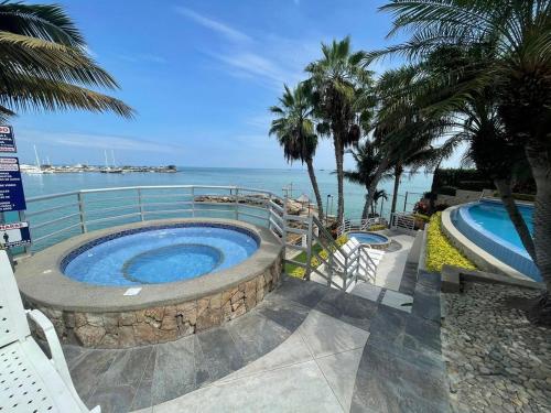una piscina junto al océano con palmeras en DEPARTAMENTO FRENTE AL MAR TM, en Salinas