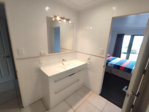 a bathroom with a sink and a mirror and a bed at panoramic vista with sea views in New Plymouth