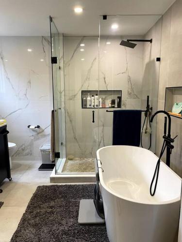 a bathroom with a bath tub and a shower at Modern, Spacious & Great Location Home in Mississauga