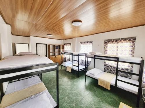 a room with three bunk beds and a wooden ceiling at Golda Coast Resort - Oslob in Oslob