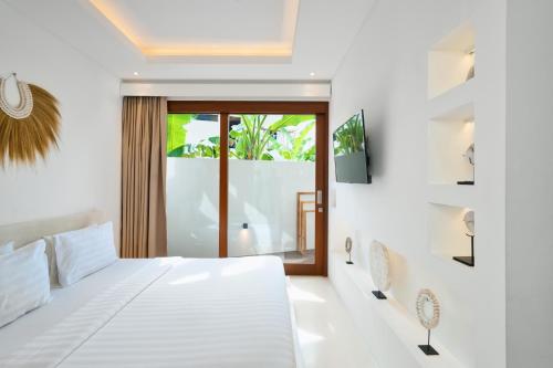 a white bedroom with a bed and a window at Pagi Villas by Betterplace in Canggu